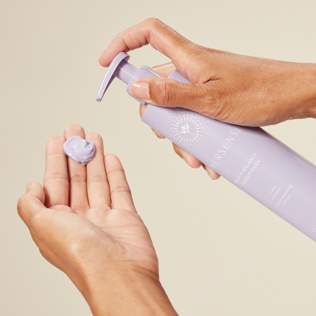 El acondicionador Bright Balance siendo dosificado sobre la mano, con textura rica y pigmentada.