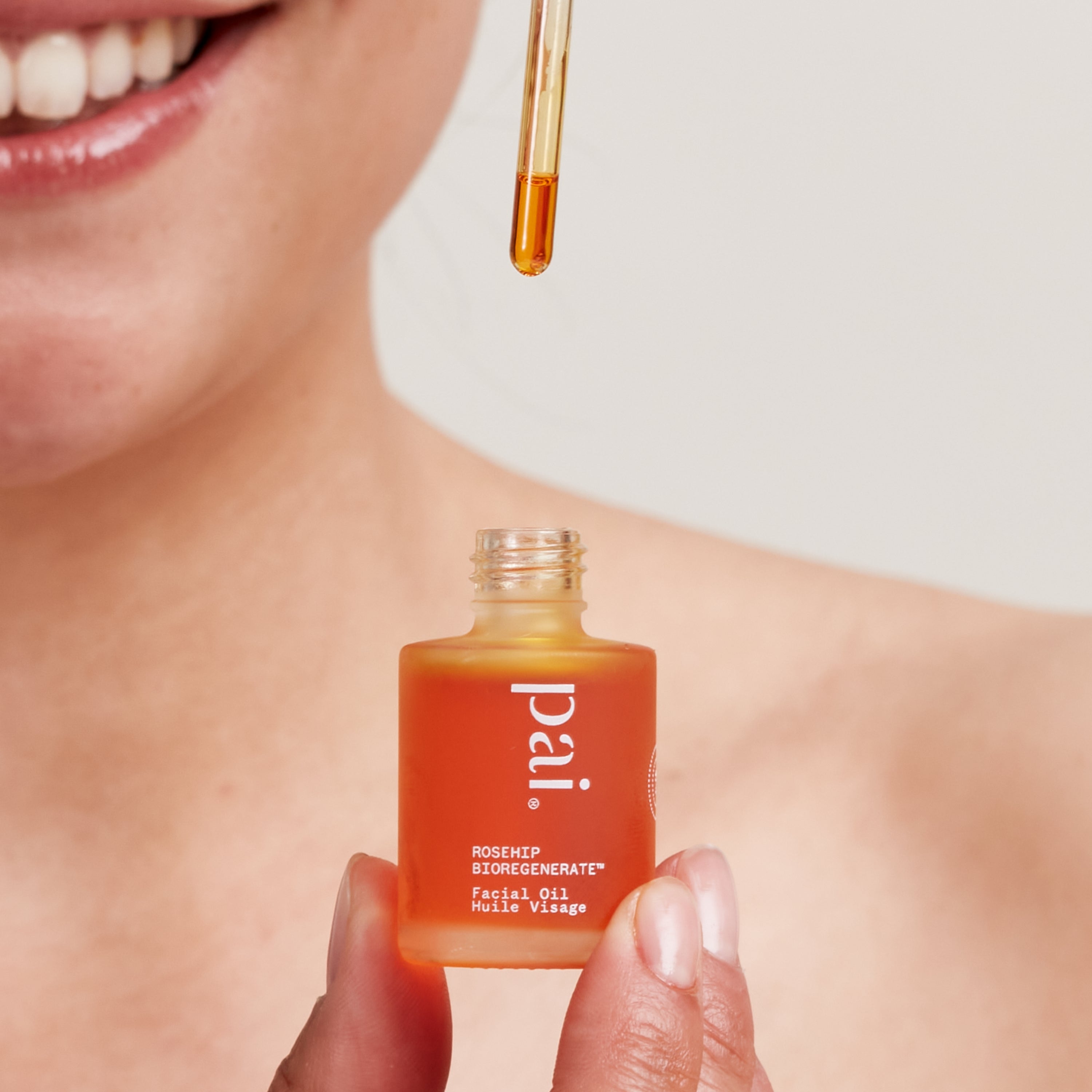 Rostro sonriente con Mini Rosehip Bioregenerate en mano, un clásico reparador con poder visible gota a gota.