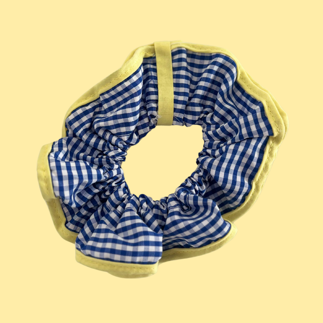 Scrunchie hair tie de La Crème Organics. Coletero para pelo abultado de cuadros azules y remate amarillo para looks veraniegos.