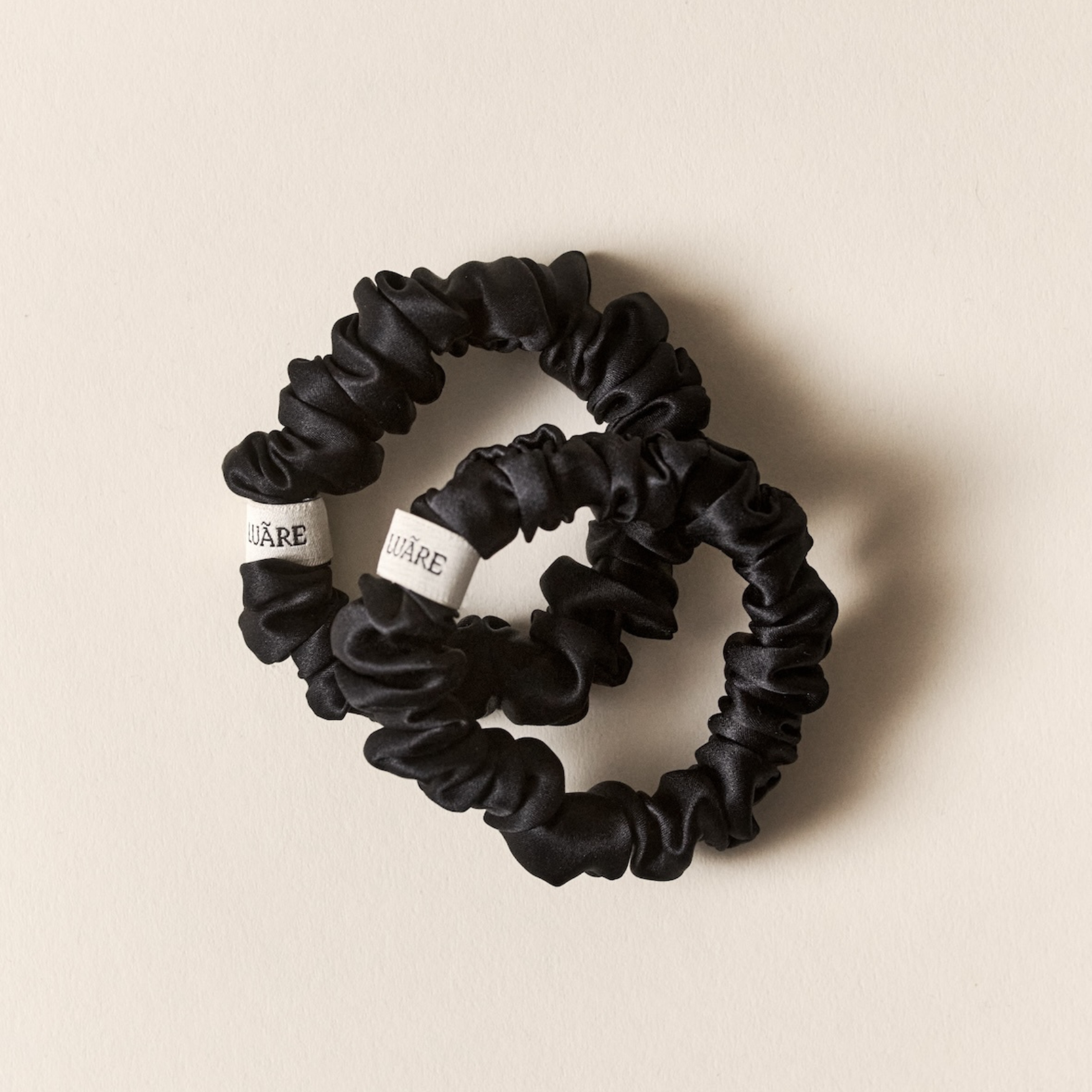 Los scrunchies de seda negra aportan estilo, sujeción delicada, brillo natural y menos encrespamiento.