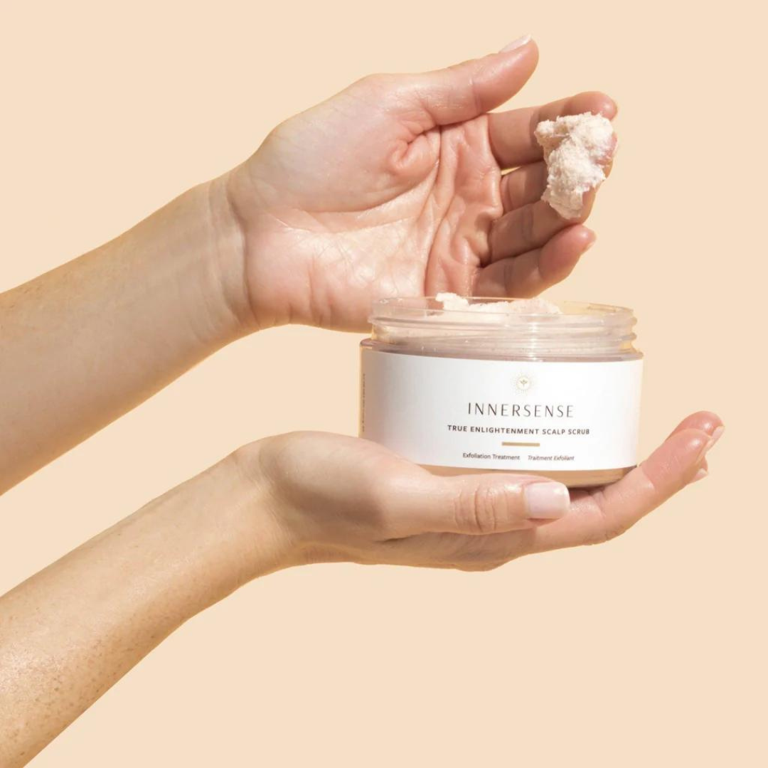 Mano cogiendo True Enlightenment Scalp Scrub desde el tarro, ideal para purificar la raíz.