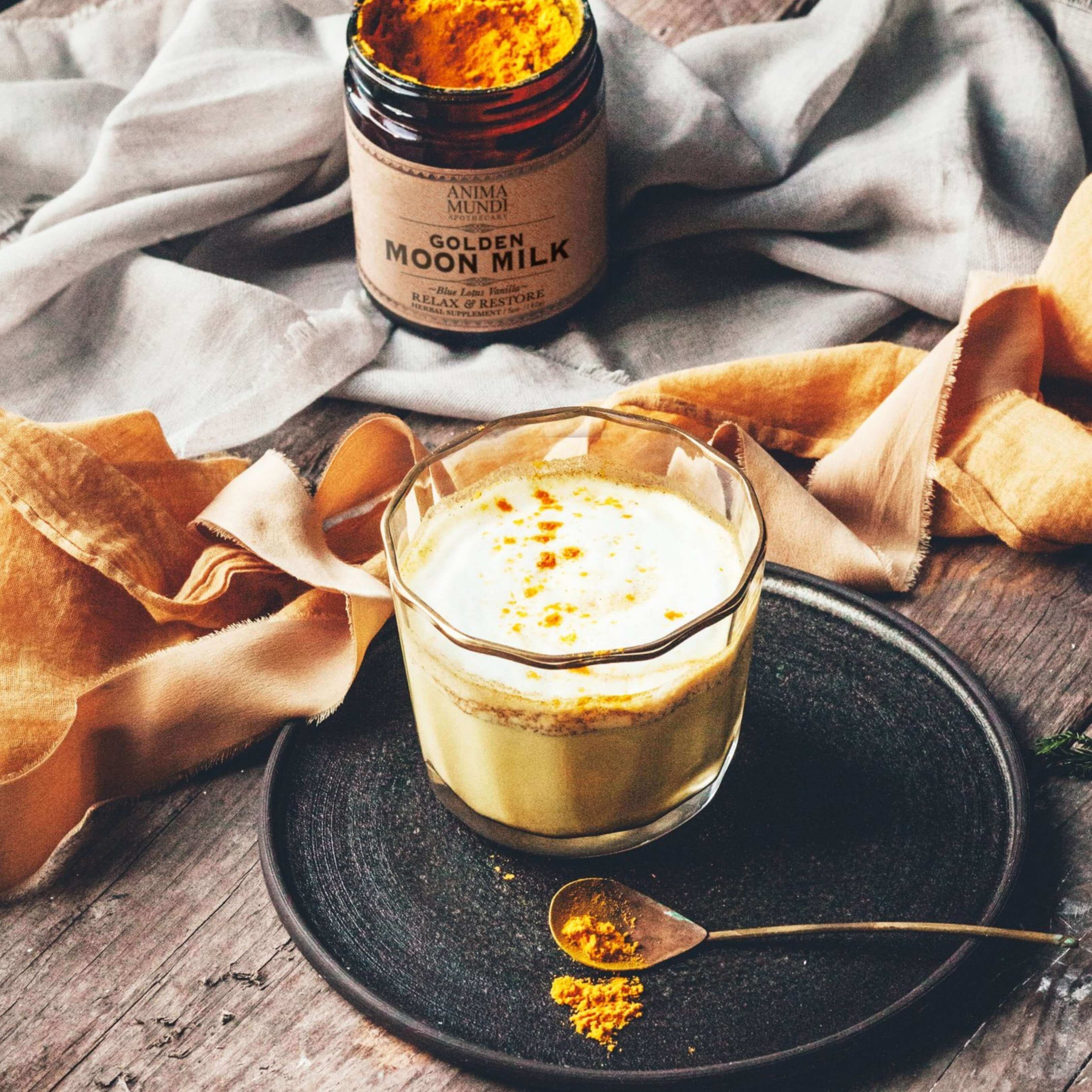 Infusión de Golden Moon Milk en taza sobre bandeja. Ritual nocturno con cúrcuma y adaptógenos para descanso profundo y mente en calma.