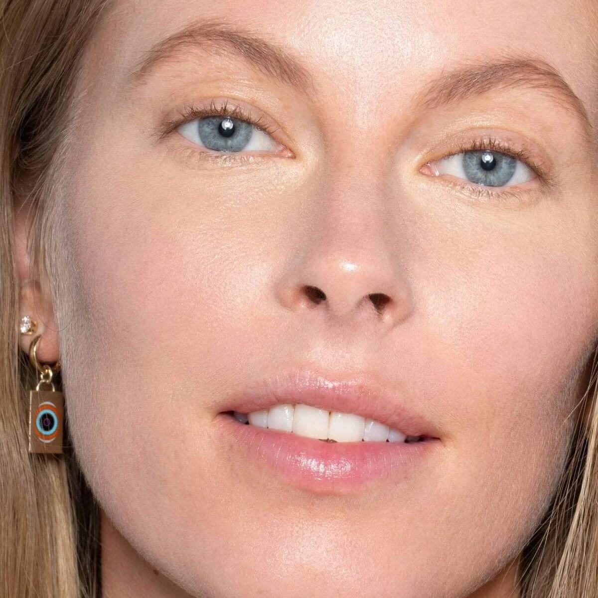 Mujer sonriendo con el tono 'Yucca SC2' del corrector de ILIA aplicado en la piel, acabado natural y luminoso.