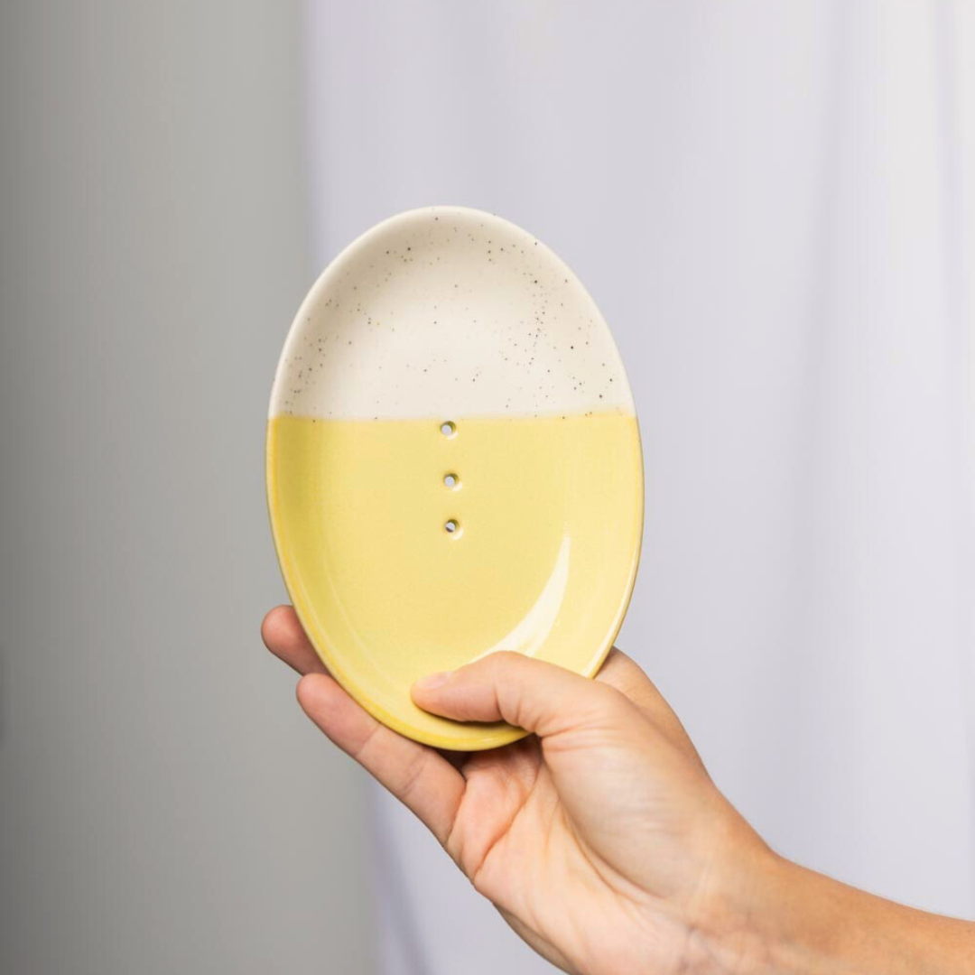 Jabonera rústica en color amarillo con tres agujeros centrales para drenar el agua del jabón sólido. Jabonera ovalada bicolor con diseño minimalista.