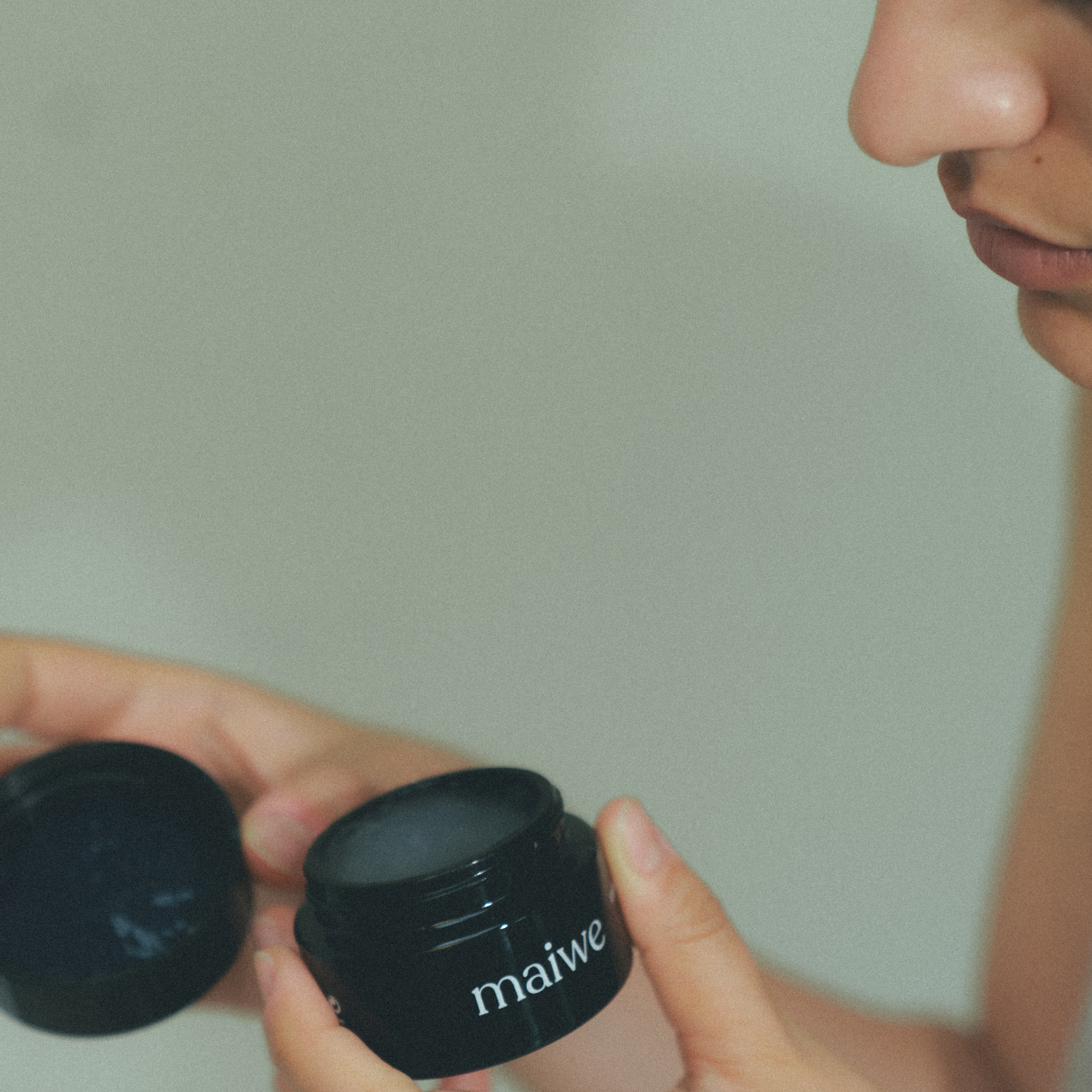 Mujer sostiene la mascarilla exfoliante abierta antes de aplicarla, mostrando su formato y textura en crema.