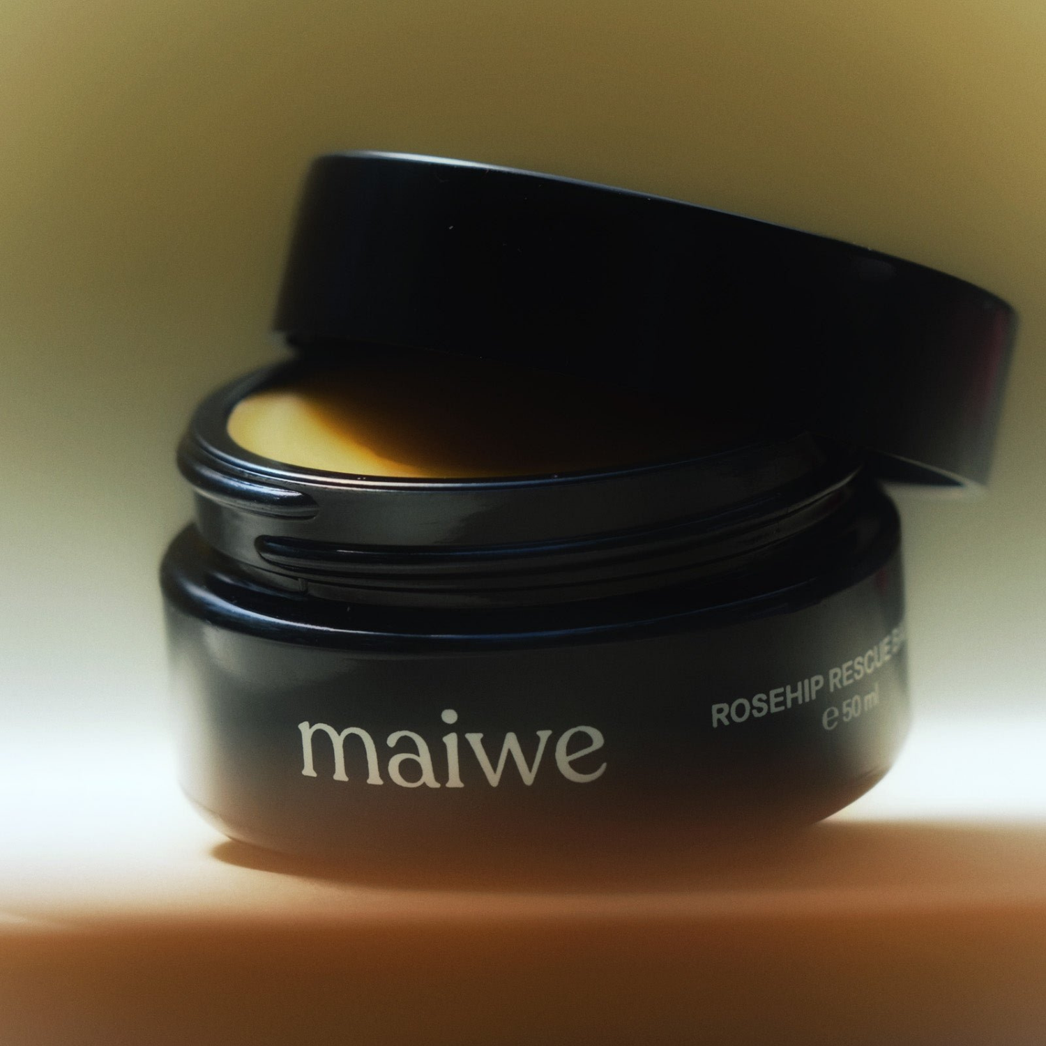 Rosehip Rescue Balm de Maiwe abierto, mostrando la textura rica del bálsamo lista para proteger la piel.