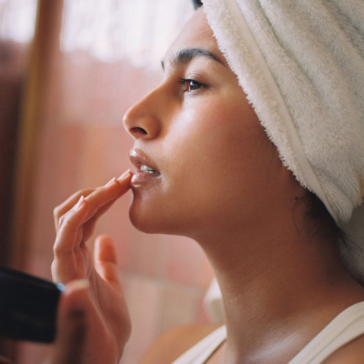 Mujer aplicando el bálsamo en los labios, resaltando su uso como cuidado nutritivo para zonas resecas.